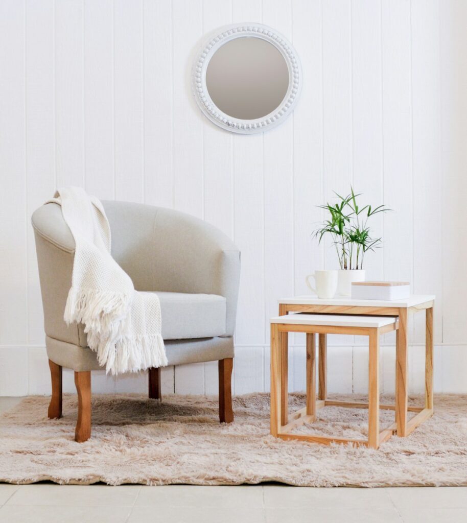 A cozy armchair with a throw blanket and side tables.